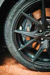 Home Detailed photo of a black alloy wheel with visible water droplets and a prominent Brembo brake caliper.